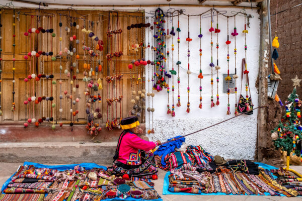 An Indigenous Woman In Traditional Costume Displaying The Traditional Method Of Weaving Wool In The Town Of Pisac, The Sacred Valley, Calca Province