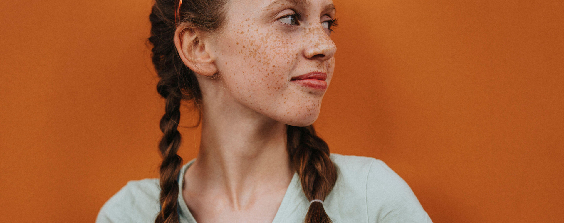 Smiling girl with braided hair looking away against orange metal structure