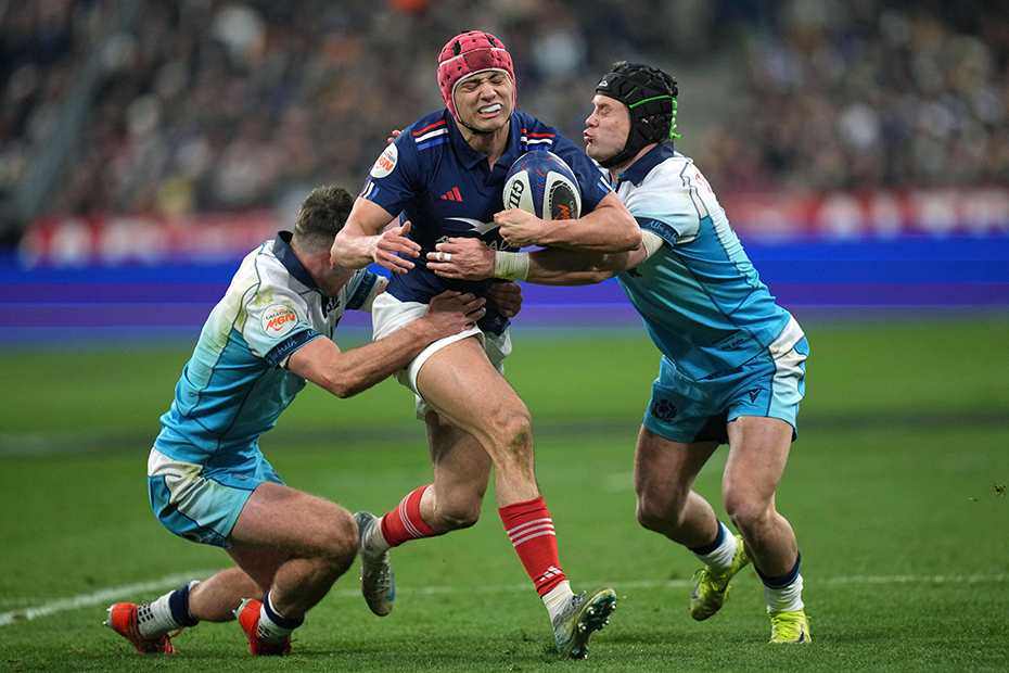 France's Louis Bielle-Biarrey, center, is tackled by Scotland's Darcy Graham, right, during the Six Nations rugby union match between France and Scotland at the Stade de France 