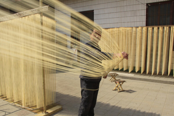 A Chinese noodle maker dries noodles at a workshop in Huangxian county, Anyang city, central China's Henan Province